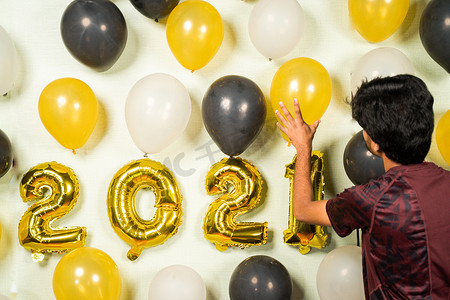有选择地关注手持气球，2021 年新年派对装饰的概念 — 年轻人忙于用气球装饰墙壁以庆祝新年派对。
