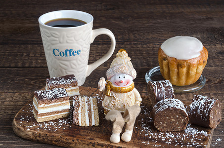 不同的蛋糕、玩具雪人和木质表面上的咖啡。