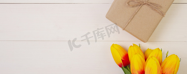 美丽的郁金香花和礼品盒，木制背景，浪漫，母亲节礼物，柔和色调，春季或夏季自然装饰在办公桌上，假日概念，横幅网站。