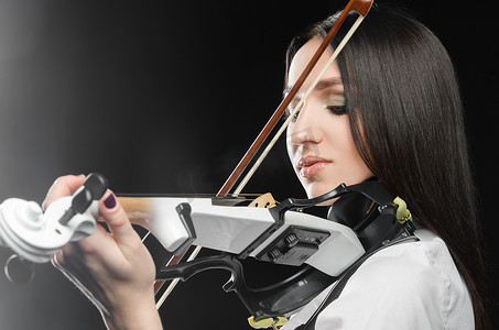 古典背景中摄影照片_黑色背景中拉小提琴的女人