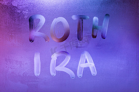 夜间经济摄影照片_夜间湿窗玻璃表面上手写的 roth ira 字样