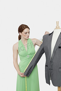灰色背景下女裁缝测量西装的袖子