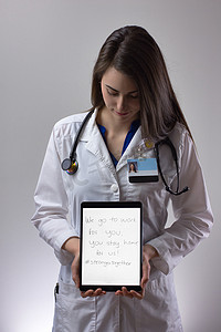 女性医护人员拿着平板电脑对着相机。