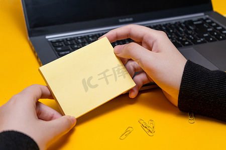 女人手拿着空白便条在笔记本电脑旁边写下新的信息更新想法。 