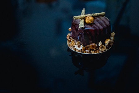镜面背景摄影照片_豪华巧克力蛋糕蛋糕装饰着深色背景上的焦糖爆米花金色装饰。