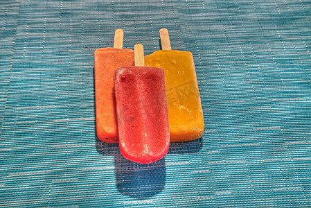 蓝色清爽夏季摄影照片_夏季水蓝色背景中的水果冰棒