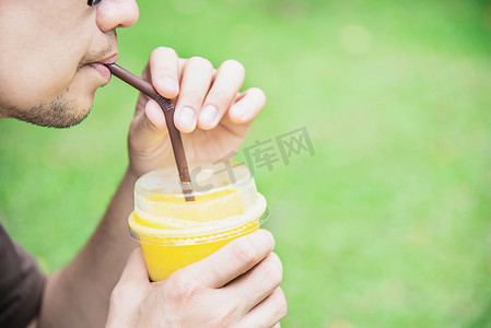 男人在绿色花园里喝冰芒果橙混合 — 用冷果饮料概念放松人们