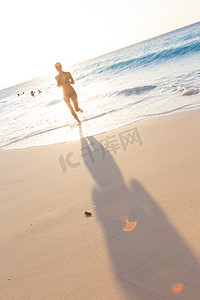 夕阳下在沙滩上奔跑的女人。