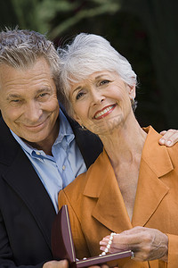 幸福的老年夫妇手牵着手拿着礼盒站着的肖像