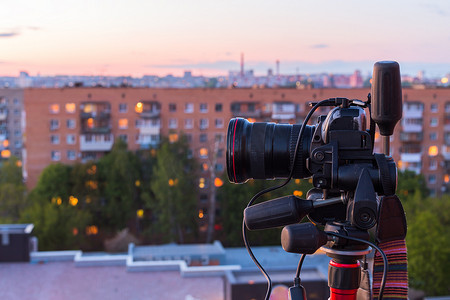 红色数码摄影照片_傍晚屋顶拍摄中三脚架上的专业数码单反相机