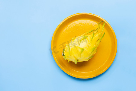 黄色火龙果或火龙果在蓝色背景的黄色盘子上。