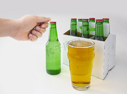 pilsner摄影照片_一个人打开 Pilsner Style Lager 绿色瓶装啤酒和一品脱啤酒