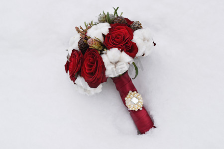 雪地玫瑰摄影照片_雪地里的玫瑰和球果花束。