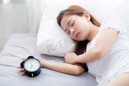 早睡觉摄影照片_美丽的亚洲年轻女性早上好关掉闹钟