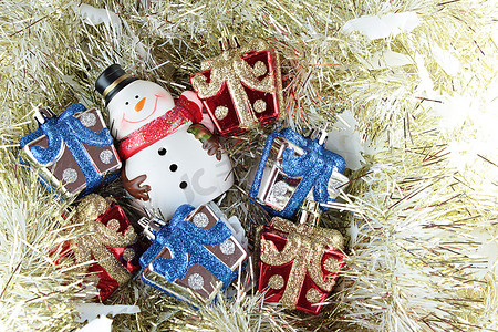 可爱的雪人和圣诞礼品盒或金色流光或金属丝背景上的礼物