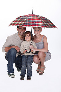 蹲下在伞下的年轻家庭