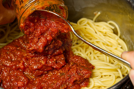 在锅里的意大利面条上加入肉酱。