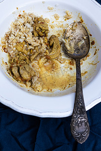 深蓝色背景的白色盘子里剩下的辣鸡肉咖喱和米饭。