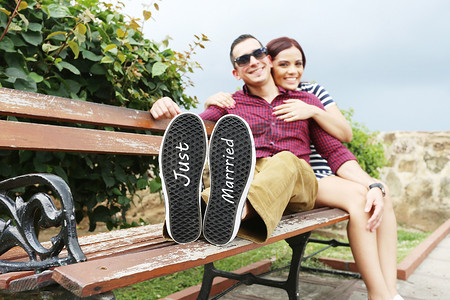 绿色的运动鞋摄影照片_年轻漂亮的夫妇在他的鞋子上写着“刚结婚”的字样。
