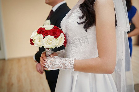 新娘在仪式上手捧一束白玫瑰和红玫瑰