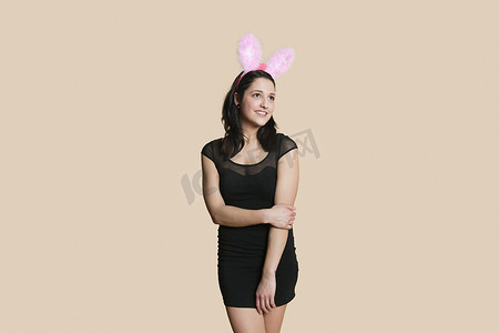 戴着兔耳的快乐年轻女人在彩色背景中望向别处