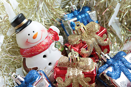 可爱的雪人、圣诞礼盒或礼物，以及金色飘带或金属丝背景的圣诞老人屋