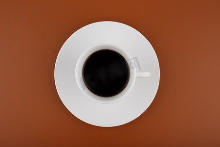 棕色背景下桌子上的白咖啡杯的顶部视图
