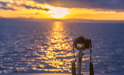 数码科技海报摄影照片_水面上的日落和数码单反相机