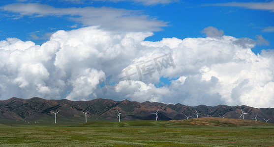 绿色草风车摄影照片_风力涡轮机或风车在绿色草地上与山脉多云蓝天背景