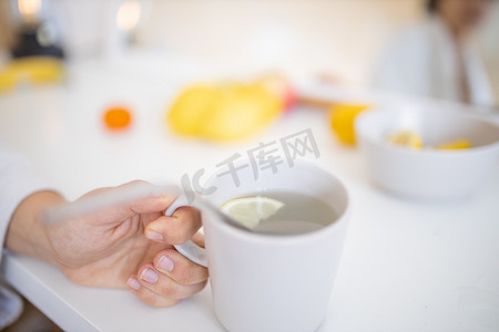 柠檬杯子摄影照片_手拿着一杯柠檬茶，上面有吸管和柠檬片