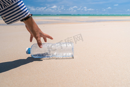 在美丽的海滩上用手捡起空水瓶或垃圾。