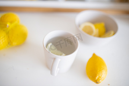 一杯柠檬茶放在一张被柠檬包围的白桌上