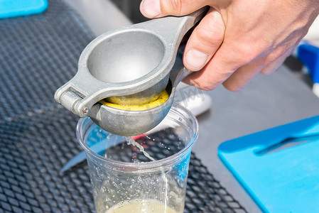 塑料杯中的手动金属榨汁机柠檬