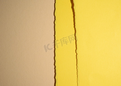 米色背景上黄色纸板撕裂的边缘，带阴影的抽象背景