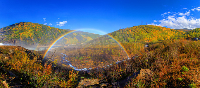 全尺寸摄影照片_全尺寸美丽明亮的彩虹以秋天的山丘和一条小溪为背景。