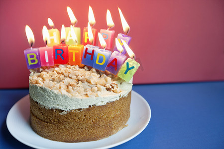 彩色背景下生日蛋糕上燃烧的蜡烛特写