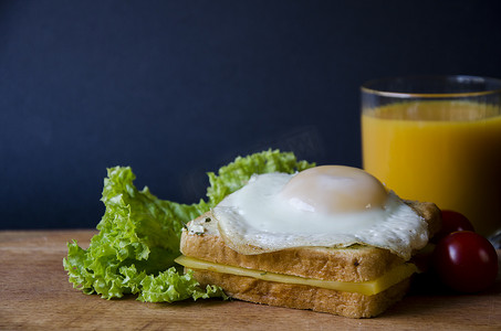 健康的三明治配奶酪和容易煎的鸡蛋，放在木板上，配沙拉、番茄和橙汁。