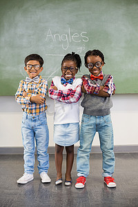 三名学童双臂交叉靠在黑板上的肖像
