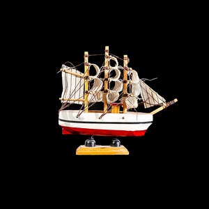 黑色背景中孤立的木架上的玩具船帆船