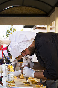 糖果厨师烹饪甜点场景，厨师装饰蛋糕，并在城市节的第比利斯街头工作。