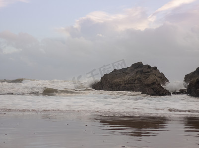 在英国威尔士高尔的卡斯威尔湾海滩，随着潮水涌入，海浪拍打着一块大岩石。