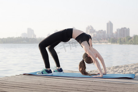 弧形桥摄影照片_运动灵活的女人在弧形桥瑜伽练习中伸展