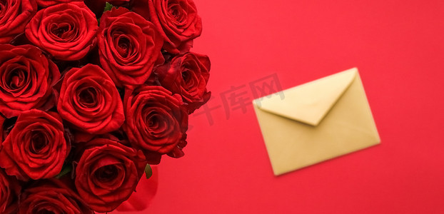 鲜花红色背景摄影照片_情人节的情书和送花服务、豪华的红玫瑰花束和红色背景的卡片信封