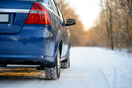 雪道上装有冬季轮胎的蓝色汽车。
