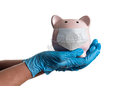 医院财务摄影照片_医生或护士戴着手术手套拿着存钱罐，戴着医疗面罩被白色隔离。