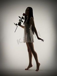 年轻女孩的剪影与灰色的玫瑰花