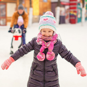 溜冰场的可爱的小女孩与父亲和姐妹