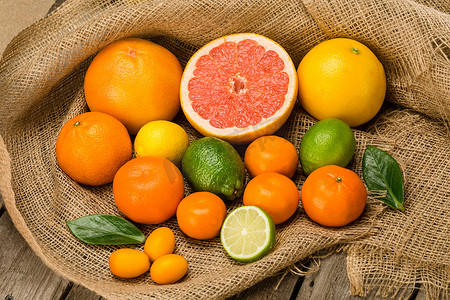麻布上各种完整和切片的新鲜柑橘类水果的特写视图