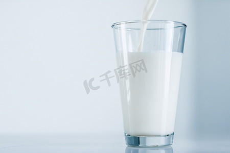 世界牛奶日，倒入大理石桌上的玻璃杯中