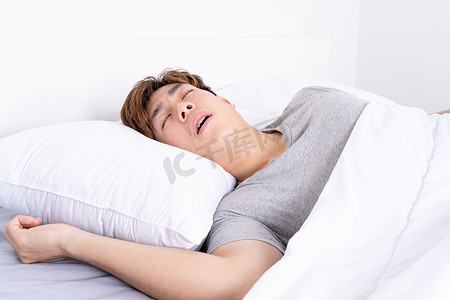 男子因工作疲倦而大声打鼾，躺在床上睡眠呼吸暂停。